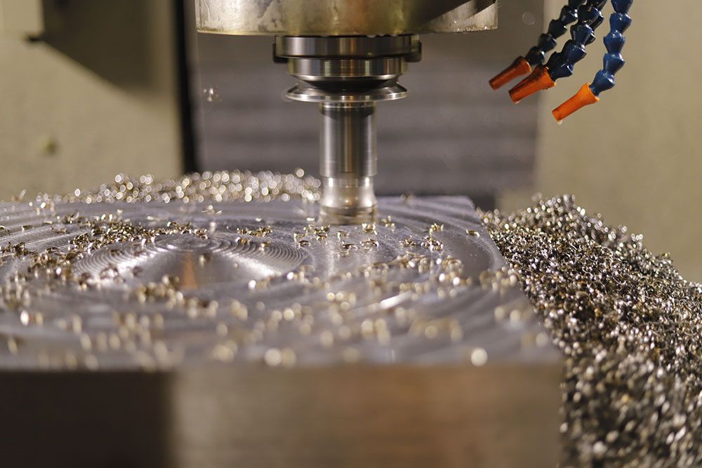 CNC tezgâhında metal bir plakanın frezelenmesi; talaşlar yüzeyde görünüyor